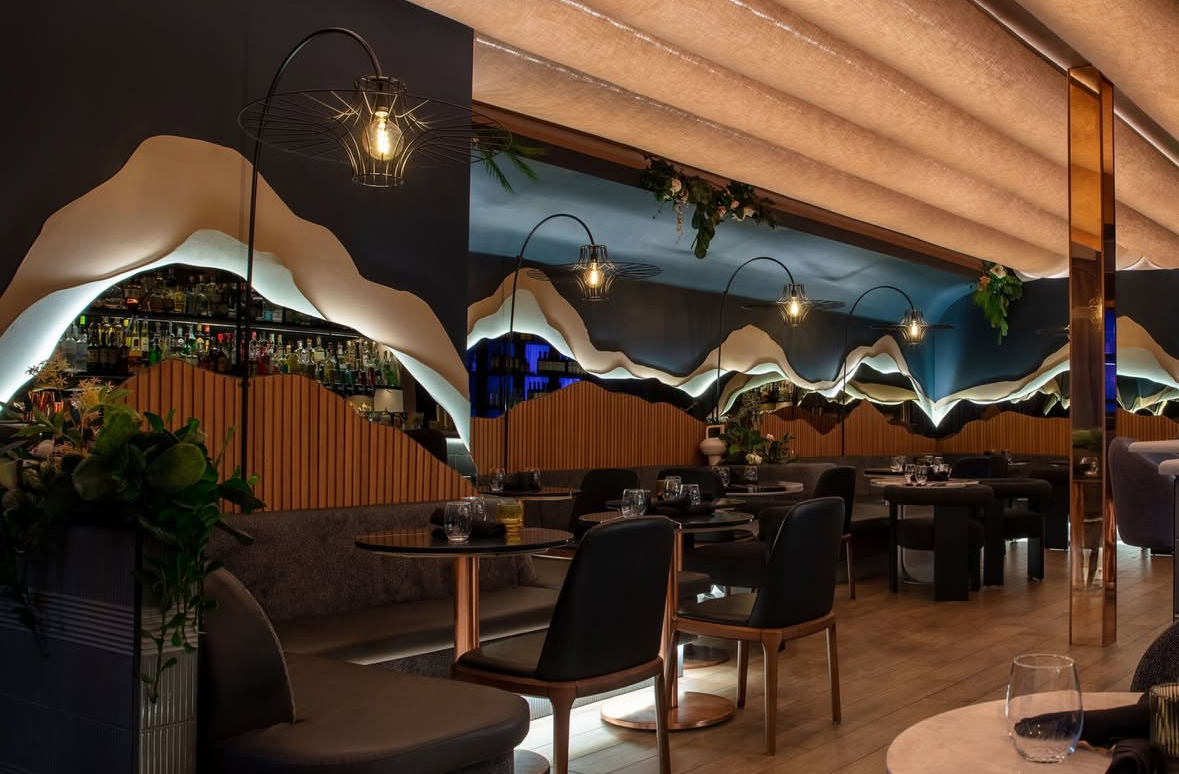 Salle de restaurant avec banquette signée et décorations murales évoquant des paysages de montagne