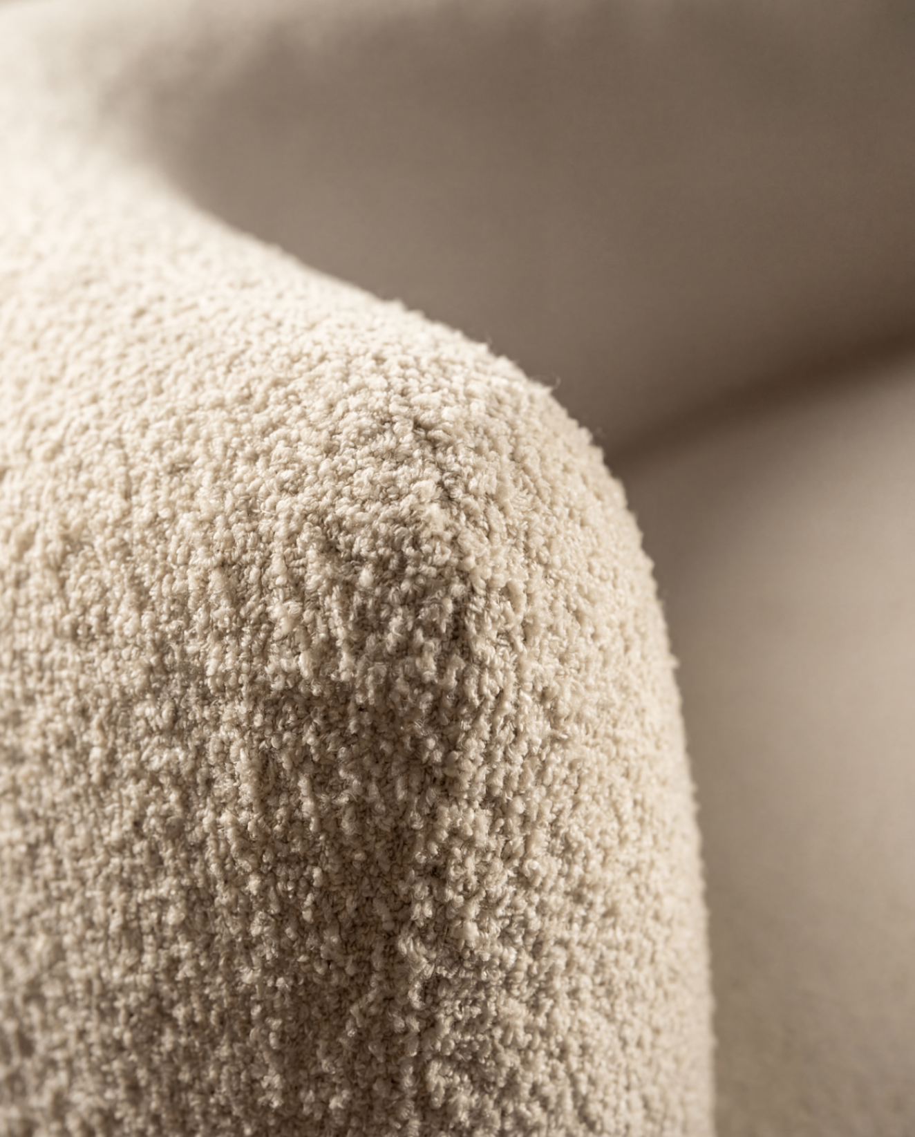 Gros plan sur un tissu bouclé ivoire, matière tactile utilisée par l'atelier pour ses rembourrages sur mesure